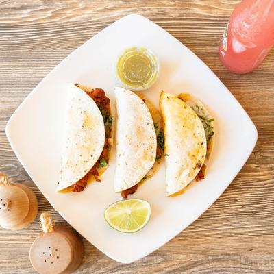 Al Pastor Tacos served with dip on the side and a drink.