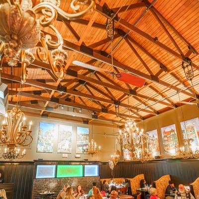 Dining room with chandeliers and wooden ceiling beams.