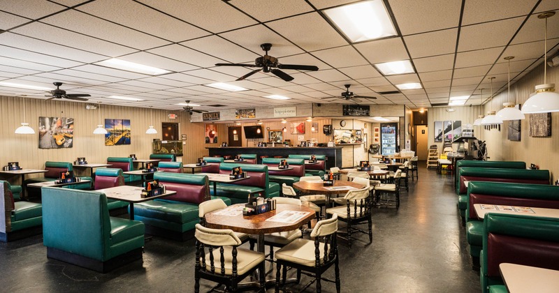 Interior, open space dining area, booths with tables, regular tables for four, ceiling fans