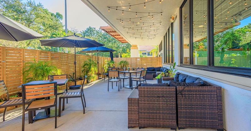 Partly covered patio area with tables, chairs and outdoor lounge sofas