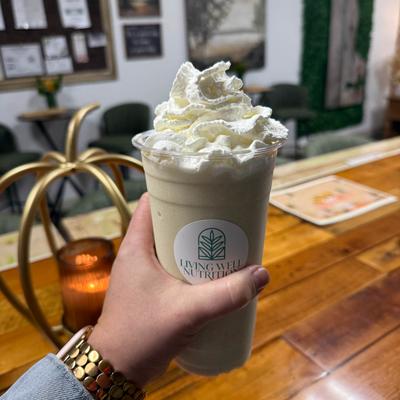 Hand holding a large, whipped-cream-topped shake.