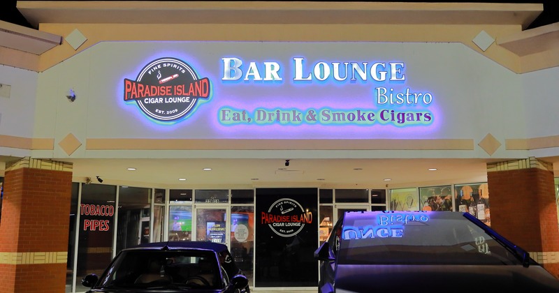 Exterior, front view to entrance, parking lot with cars in front, light sign above entrance