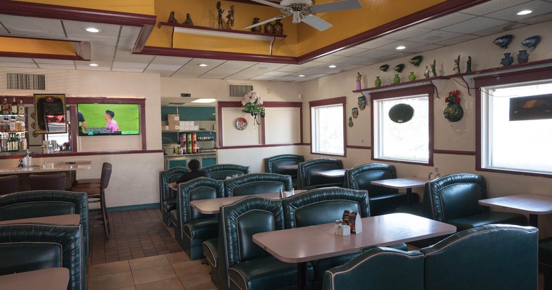 Interior, dining area, padded seating booths with tables, tile flooring, windows on the right