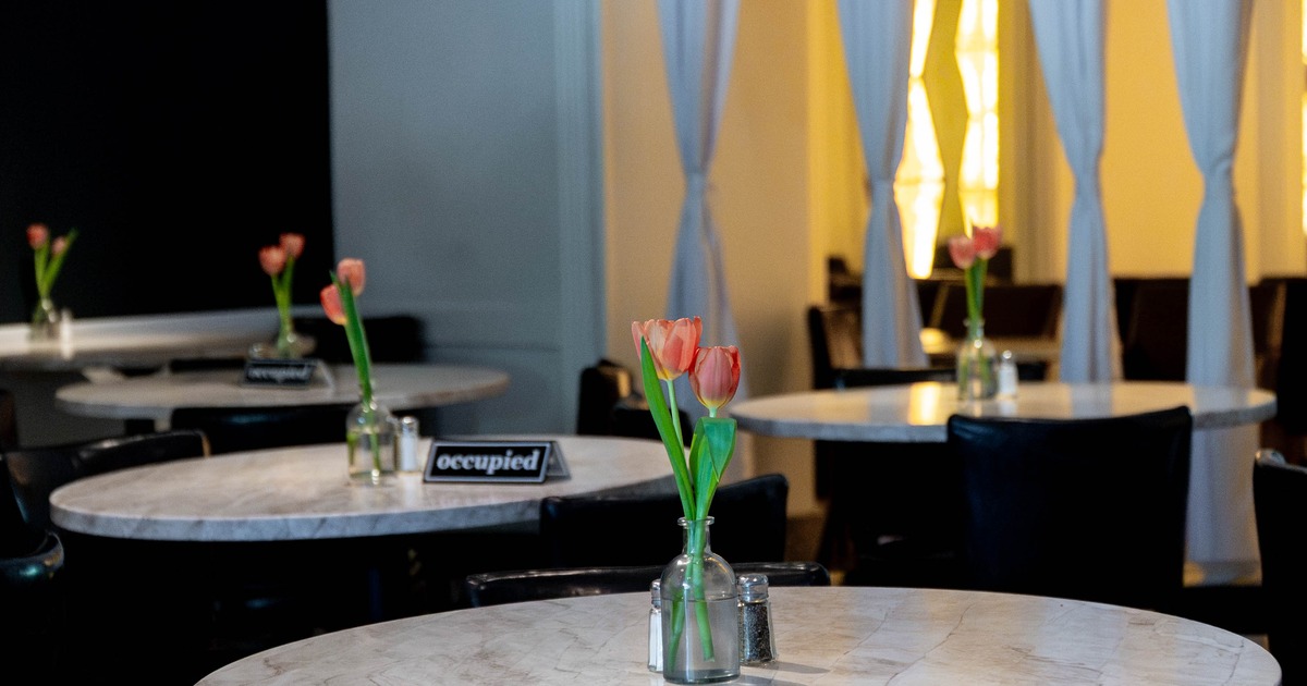 Restaurant interior with marble tables, pink tulips in glass vase