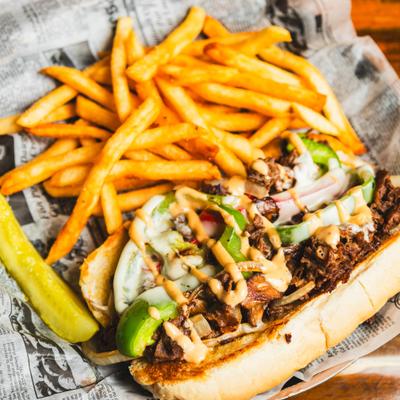 Philly cheesesteak with side fries.