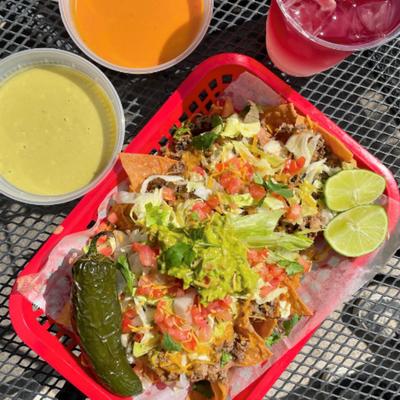 Loaded nachos servd with two dips and a drink.