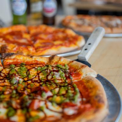 Pizza topped with tomato sauce, mozzarella, a pesto drizzle, and a balsamic glaze.