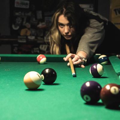 A person playing pool, angled view.