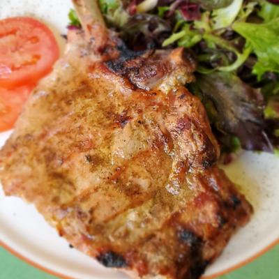 Grilled veal chop alongside mixed greens.