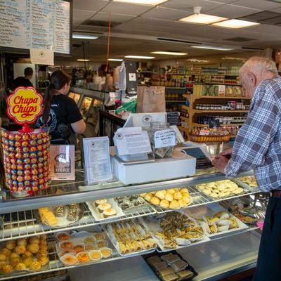 A customer standing at a bakery counter with freshly baked goods and pastries.