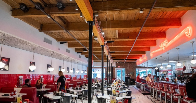 Interior of a retro-style diner with red booths, wooden ceiling, and neon lights