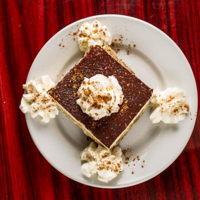 Tiramisu garnished with five dollops of whipped cream and a dusting of cocoa powder.