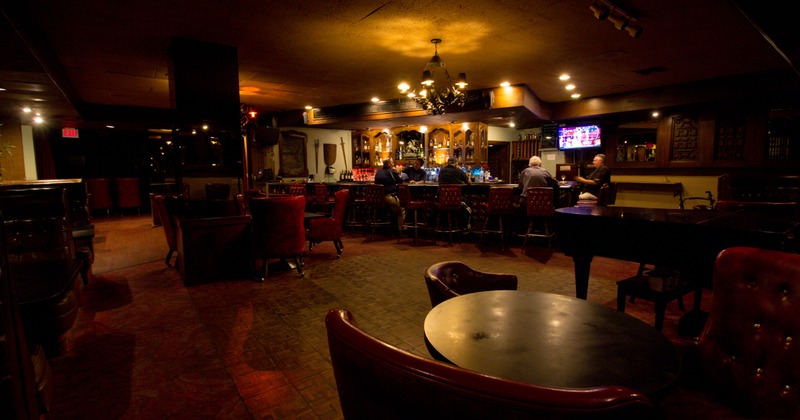 Interior, dim lit seating area and a bar illuminated by chandelier light