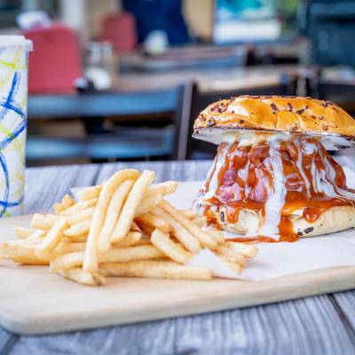 Super Roast Beef Sandwich with dripping sauces on an onion roll, served with fries.