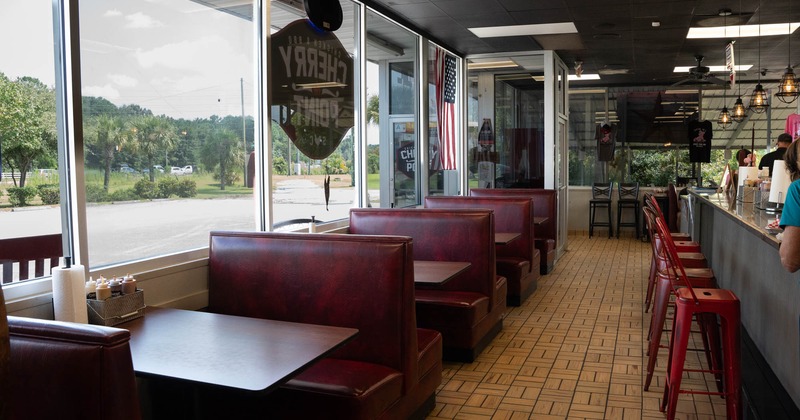 Interior, leather padded seating booths with tables, entrance, large shop window