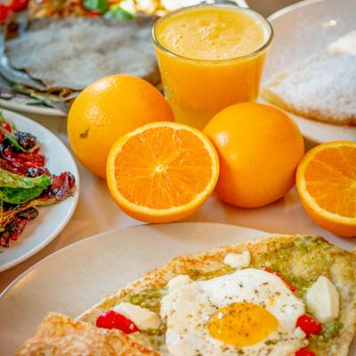 Caprese crepe topped with a fried egg, served with fresh oranges and orange juice.