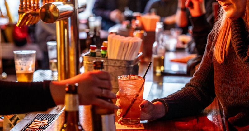Bar close up shot, patrons enjoying drinks, bar staff serving drinks