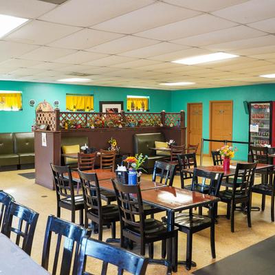 Interior with wooden tables, chairs, teil walls, and flower arrangements.