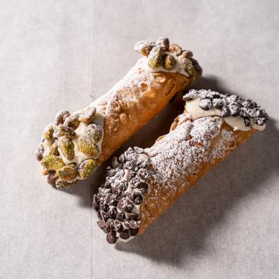 Cannoli topped with mini chocolate chips and chopped pistachios.