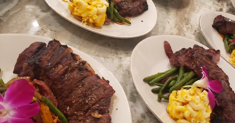 Several plates of steak with side dishes