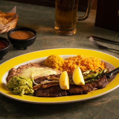 Traditional Carne a La Parrilla with sides of rice, beans and guacamole.