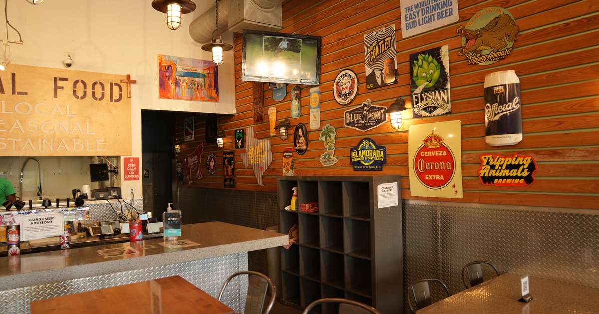 Interior of a casual restaurant with vintage beverage signs and a metal counter.