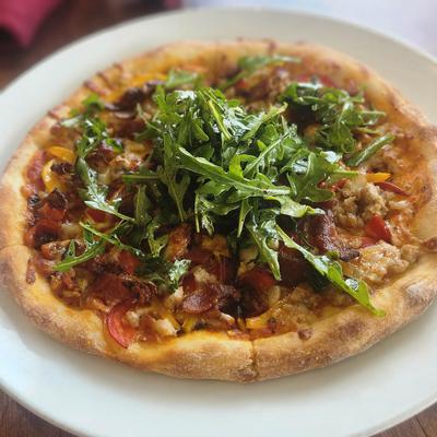 Prosciutto and Arugula Pizza served on a white plate.