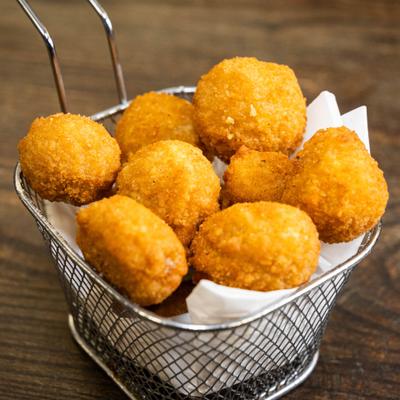 Fried mushrooms served in a stainless steel mini fryer basket.