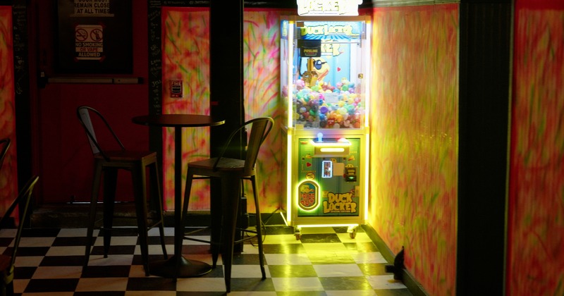 Bar table, stools, toy machine behind