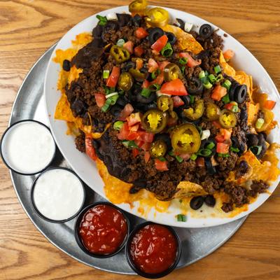 Ground beef nachos, with tomato, scallions, jalapenos, olives, beans, salsa, and sour cream.
