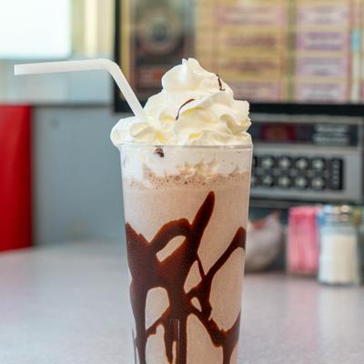 Chocolate milkshake topped with whipped cream and a chocolate drizzle.