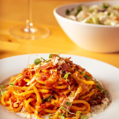 Spaghetti marinara with cheese and herbs, tri colore salad in the background.