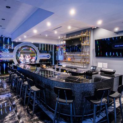 Modern bar with black counter, stools, and neon wall lights.