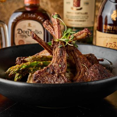 Herb-crusted lamb chops with garlic butter sauce, asparagus, and microgreens.