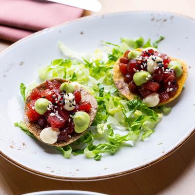 Two tuna tostadas served on a bed of lettuce.