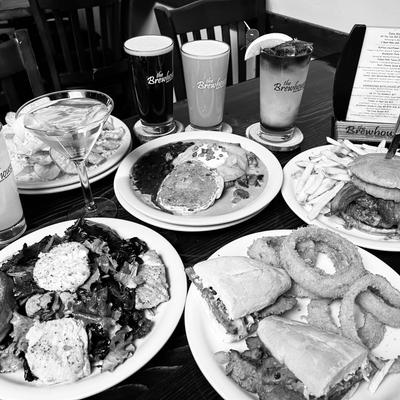 Assorted restaurant meals with burgers, sandwiches, fries, and drinks on a table.