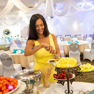 A guest at a wedding banquet serving fruit from a dessert table.