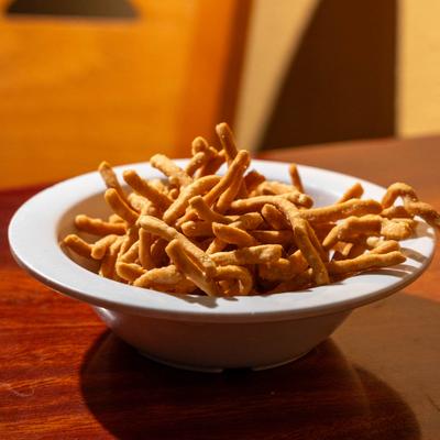 A bowl of crunchy noodles on a wooden table.