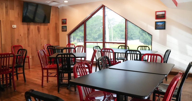 Interior, seating area with black and red chairs, TV on the wall