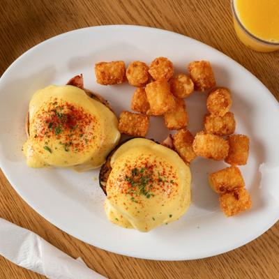 Eggs Benedict served with tater tots, overhead view.