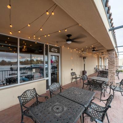Covered outdoor seating area with metal tables and chairs under string lights.