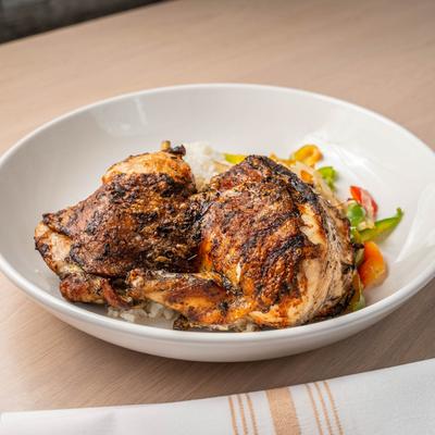 Roasted half jerk chicken with coconut lime rice, sauteed peppers and onions.