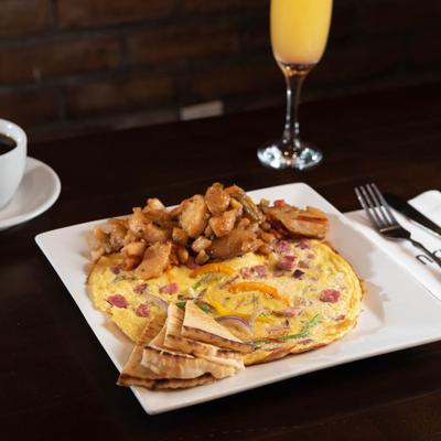 Meat and vegetable omelet served with pita and cooked potatoes, coffee and orange juice.