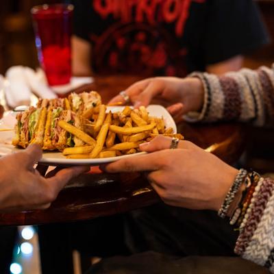 Employee handing a plate with club sandwiches and fries to a customer