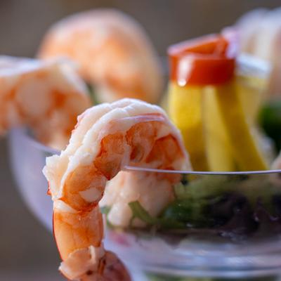 Close-up of a shrimp cocktail served in a glass with lemon garnish.
