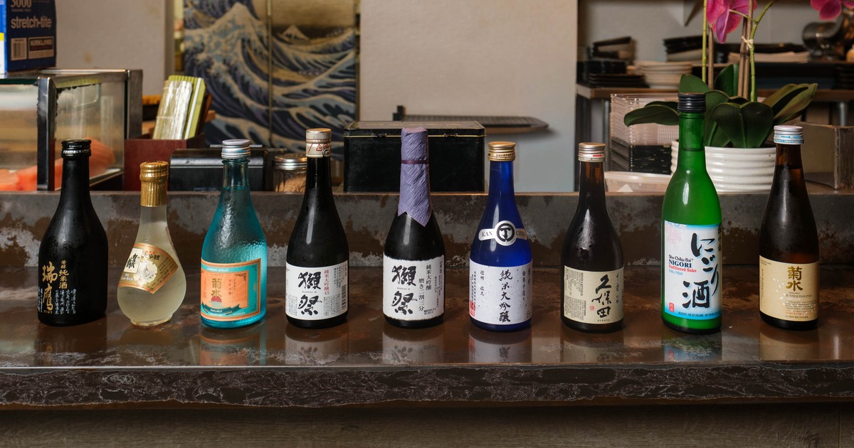 A row of selected sake bottles set on a dark marble counter