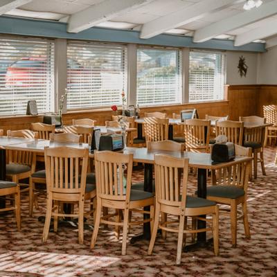 Dining room with several wooden chairs and tables arranged in rows.