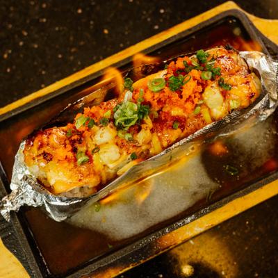 Foil-wrapped baked sushi roll with visible flames.