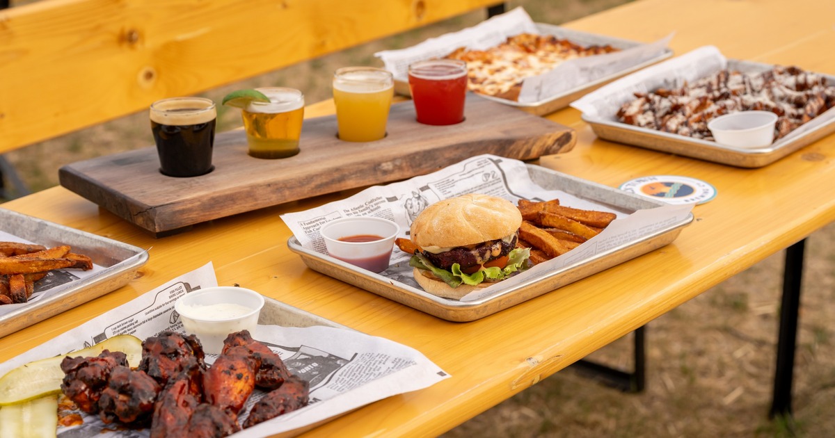 A BBQ feast featuring a burger, wings, and a beer flight