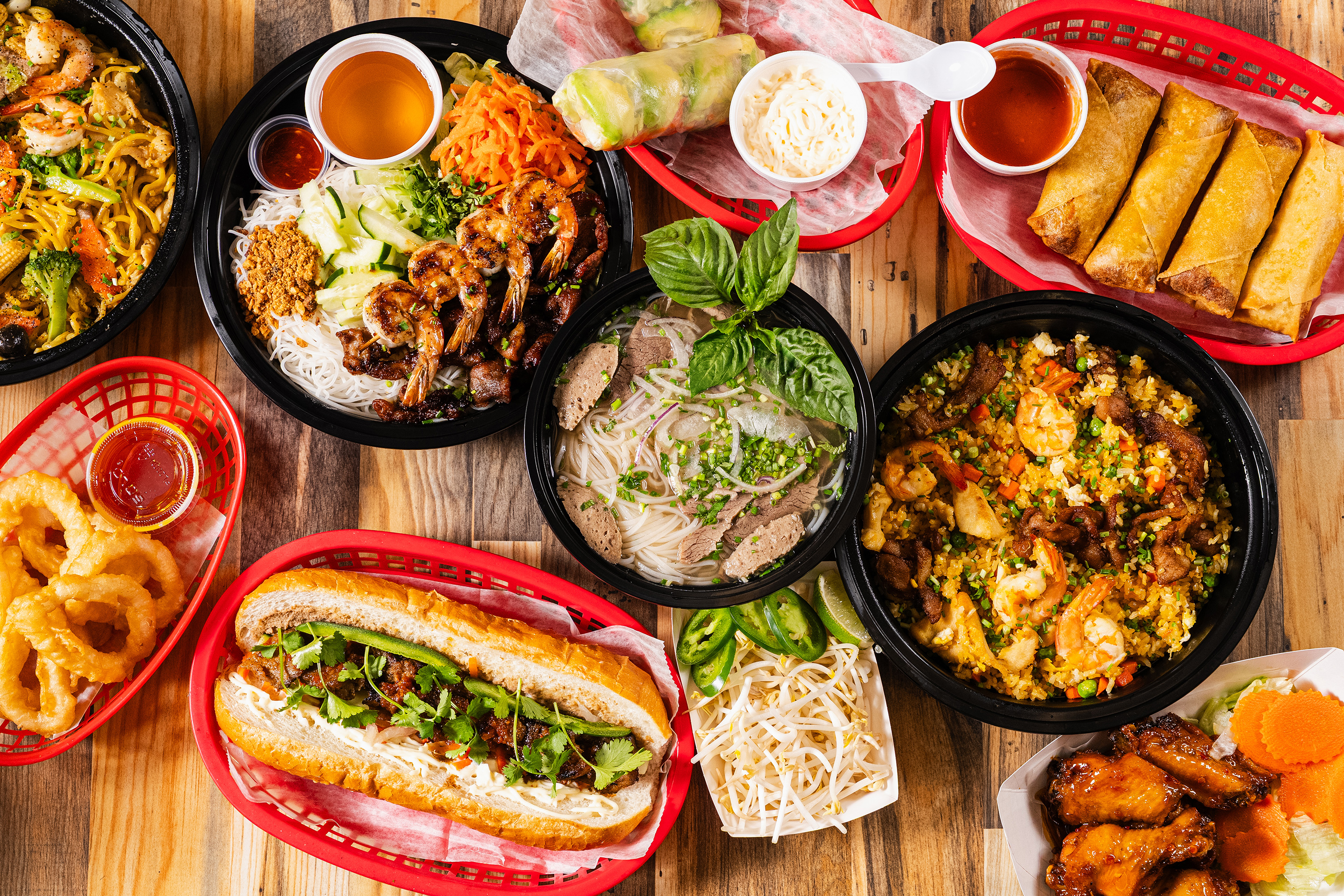 Assorted Vietnamese dishes served on the wooden table, overhead view